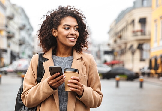 Smiling woman with coffee and phone