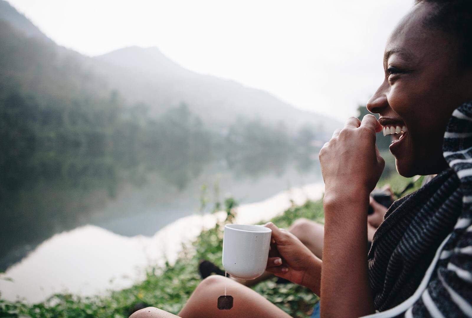 Laughing woman drinking tea in the mountains