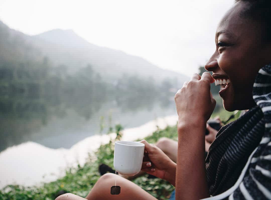 Woman laughing and drinking tea in the mountains.
